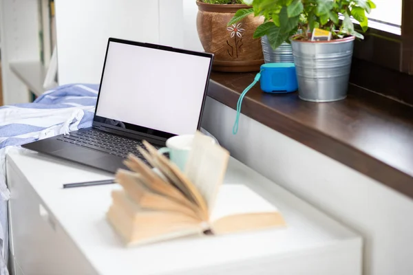 laptop and book by window at home space for your text