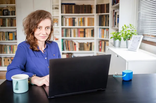 happy woman working on laptop in home office
