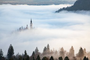 Sisli bir sabahta, Bled Blejsko Jezero Gölü 'nün muhteşem manzarası. Küçük bir adada Maria' nın Hacı Kilisesi ve arka planda Kanlı Kale ve Julian Alps.