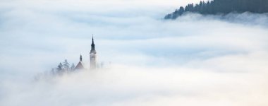 Sisli bir sabahta, Bled Blejsko Jezero Gölü 'nün muhteşem manzarası. Küçük bir adada Maria' nın Hacı Kilisesi ve arka planda Kanlı Kale ve Julian Alps.