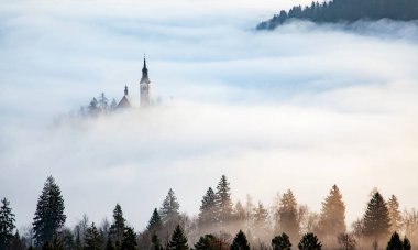 Sisli bir sabahta, Bled Blejsko Jezero Gölü 'nün muhteşem manzarası. Küçük bir adada Maria' nın Hacı Kilisesi ve arka planda Kanlı Kale ve Julian Alps.