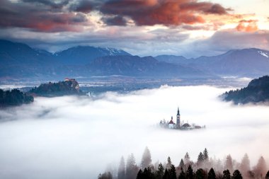 Sisli bir sabahta, Bled Blejsko Jezero Gölü 'nün muhteşem manzarası. Küçük bir adada Maria' nın Hacı Kilisesi ve arka planda Kanlı Kale ve Julian Alps.