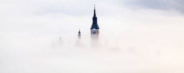Sisli bir sabahta, Bled Blejsko Jezero Gölü 'nün muhteşem manzarası. Küçük bir adada Maria' nın Hacı Kilisesi ve arka planda Kanlı Kale ve Julian Alps.