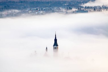 Sisli bir sabahta, Bled Blejsko Jezero Gölü 'nün muhteşem manzarası. Küçük bir adada Maria' nın Hacı Kilisesi ve arka planda Kanlı Kale ve Julian Alps.