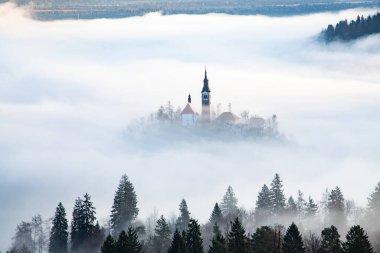 Sisli bir sabahta, Bled Blejsko Jezero Gölü 'nün muhteşem manzarası. Küçük bir adada Maria' nın Hacı Kilisesi ve arka planda Kanlı Kale ve Julian Alps.