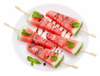 Beyaz tabakta üzerine beyaz izole sopayla karpuz dilimleri