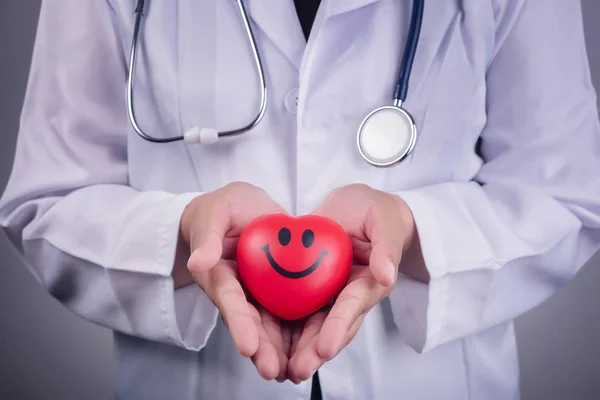 Υγιή αντίληψη - κόκκινη καρδιά μπάλα στο χέρι του γιατρού και ένα μπλε — Φωτογραφία Αρχείου
