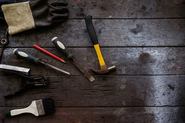 Tono vintage del equipo en escritorio de madera con el hombre trabajando en el fondo del taller. Efecto filtro retro, poca luz, enfoque selectivo . — Foto de Stock