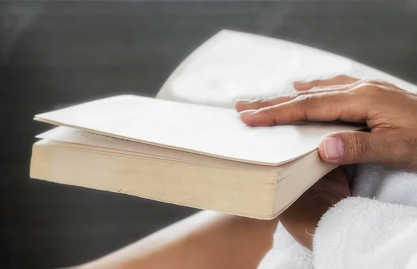 Hermosa mujer asiática sentada en la cama con una taza de café y leyendo un libro. Mañana con un libro y una taza de café. Concepto relajante. Efecto filtro retro, enfoque suave, enfoque selectivo — Foto de Stock