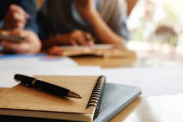 Education concept. Students studying and brainstorming campus concept. Close up of students discussing their subject on books textbooks and writing to notebook. Selective focus. Stock Picture