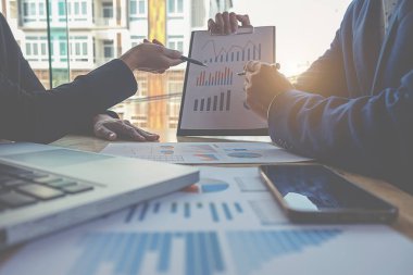 İş konsepti. İş adamları başarılı takım çalışmalarının sonuçlarını gösteren çizelge ve grafikleri tartışıyor.