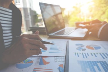 İş konsepti. İş adamları başarılı takım çalışmalarının sonuçlarını gösteren çizelge ve grafikleri tartışıyor.