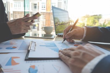 İş konsepti. İş adamları başarılı takım çalışmalarının sonuçlarını gösteren çizelge ve grafikleri tartışıyor.