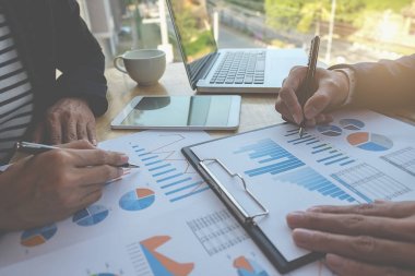 İş konsepti. İş adamları başarılı takım çalışmalarının sonuçlarını gösteren çizelge ve grafikleri tartışıyor.