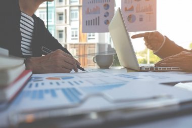 İş konsepti. İş adamları başarılı takım çalışmalarının sonuçlarını gösteren çizelge ve grafikleri tartışıyor.