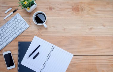 Ofis resepsiyon masası klavye, defter, kalem, bardak kahve ve çiçek ile. Kopya alanı (seçici odak ile Üstten Görünüm)