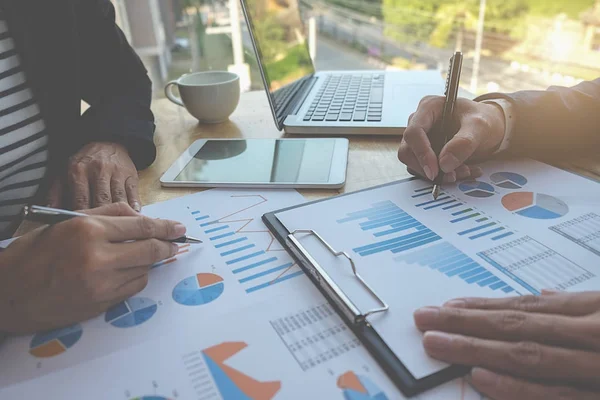 İş konsepti. İş adamları başarılı takım çalışmalarının sonuçlarını gösteren çizelge ve grafikleri tartışıyor.