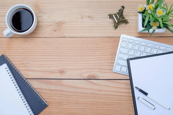 Mesa de escritorio con teclado, cuaderno, bolígrafo, taza de café y flores. Vista superior con espacio de copia (enfoque selectivo ) —  Fotos de Stock