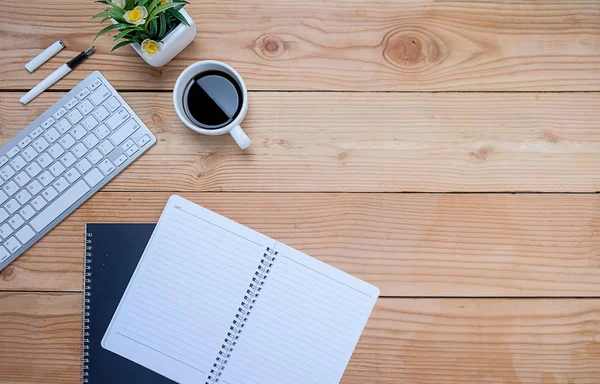 Ofis resepsiyon masası klavye, defter, kalem, bardak kahve ve çiçek ile. Kopya alanı (seçici odak ile Üstten Görünüm)