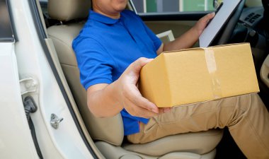 Kargo şoförü koltukta paketler ile araba kullanıyor.