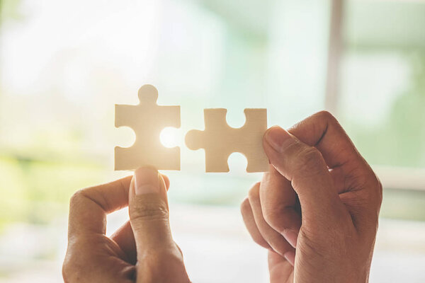 Business woman hands connecting jigsaw puzzle. Business solutions, success and strategy concept. Close up photo with selective focus.