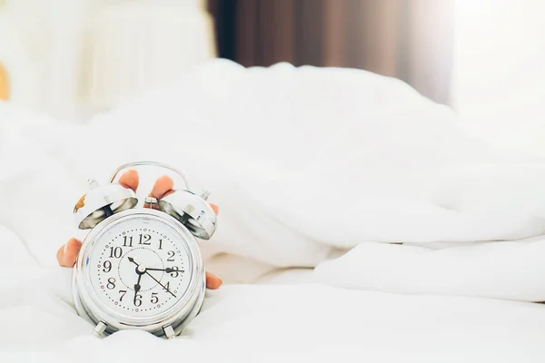 Irritated young woman putting her alarm clock off in the morning — Stock Photo, Image