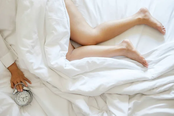 Раздраженная молодая женщина, откладывающая будильник на утро — стоковое фото