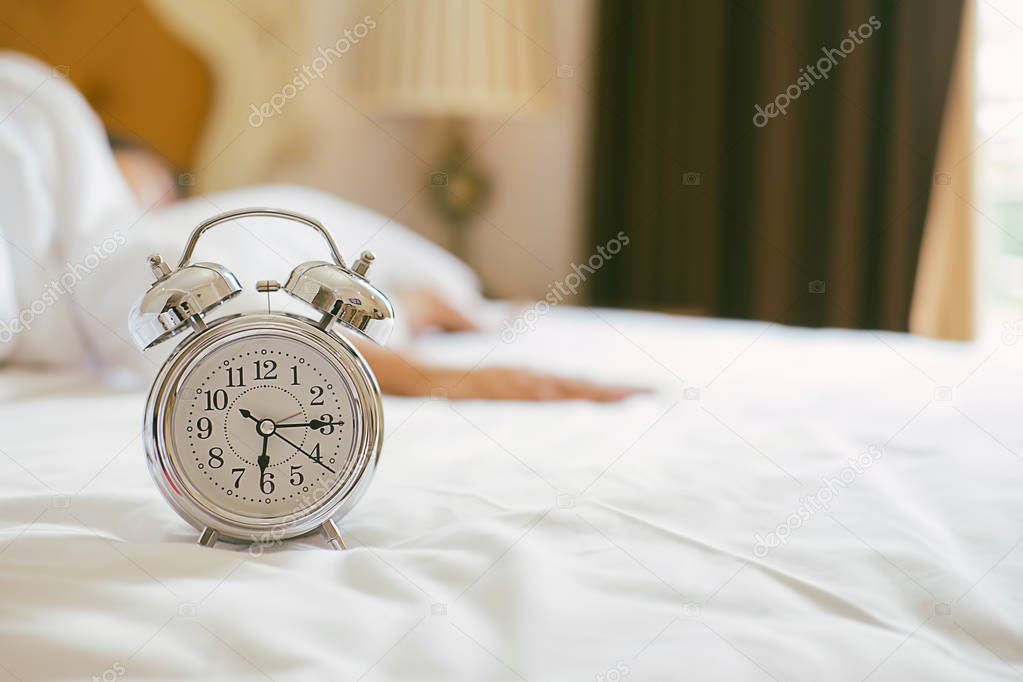 Alarm clock standing on bedside table has already rung early mor