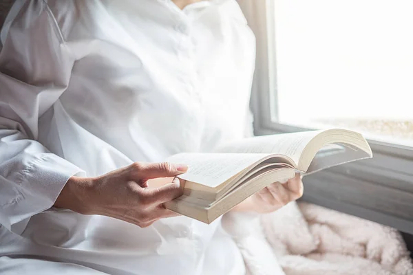 Reading a book. Beautiful female sitting on the bed and reading — Stock Photo, Image