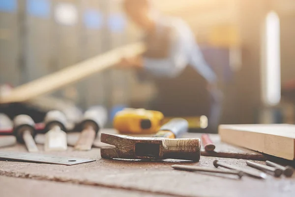 Ausrüstung auf Holztisch mit Mann im Hintergrund der Werkstatt — Stockfoto