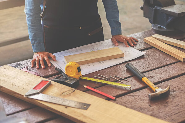 Carpenter working on woodworking machines in carpentry shop. wom
