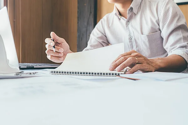 Engineers discuss a blueprint while checking information on a ta — Stock Photo, Image