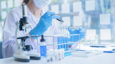 Tıbbi ya da bilimsel araştırmacı ya da insan doktoru laboratuarda bir test tüpü dolusu temiz çözeltiye bakıyor.
