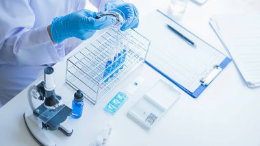 Tıbbi ya da bilimsel araştırmacı ya da insan doktoru laboratuarda bir test tüpü dolusu temiz çözeltiye bakıyor.