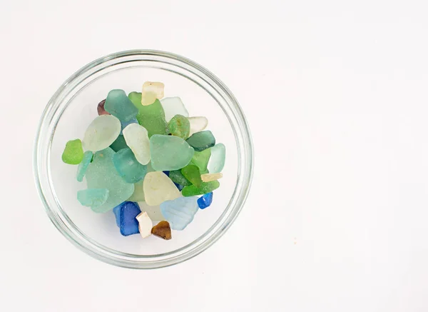 Guijarros de colores en una taza de vidrio sobre fondo blanco — Foto de Stock
