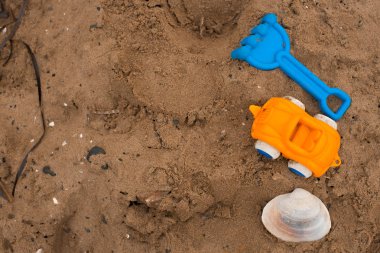 Çocuklar ve bir deniz kabuğu kuma için oyuncaklar.