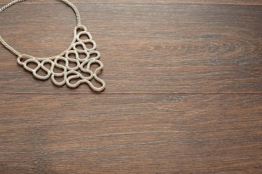 Kadın kahverengi ahşap zemin üzerinde metal kolye.