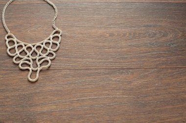 Kadın kahverengi ahşap zemin üzerinde metal kolye.