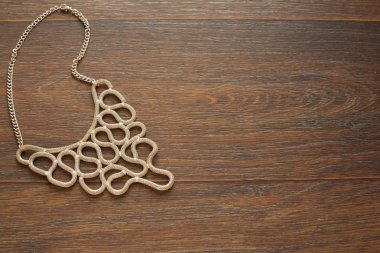 Kadın kahverengi ahşap zemin üzerinde metal kolye.