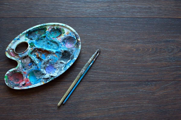 Resim paleti ve ahşap arka plan boyama için fırçalar. Üstten Görünüm.