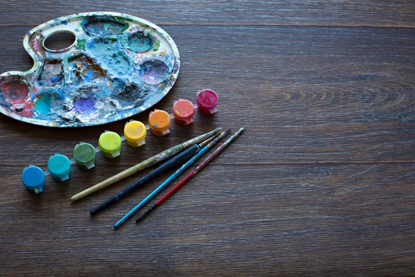Art set, palette, paint, brushes on wooden background.