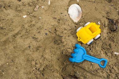 Çocuklar ve bir deniz kabuğu kuma için oyuncaklar.