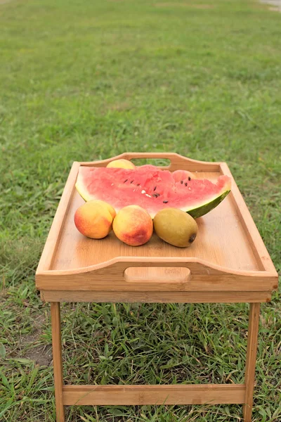 Houten tafel met vruchten op een achtergrond van groen gras. — Stockfoto