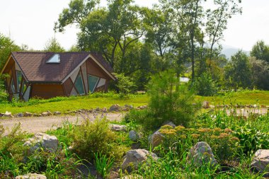 Ağaçlar, çalılar ve çiçekler arasında kır evi.