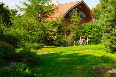 Ağaçlar, çalılar ve çiçekler arasında kır evi.