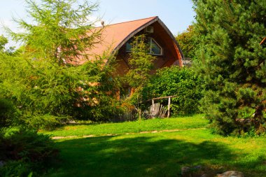 Ağaçlar, çalılar ve çiçekler arasında kır evi.