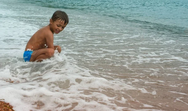 Счастливый мальчик играет в море на пляже. — стоковое фото