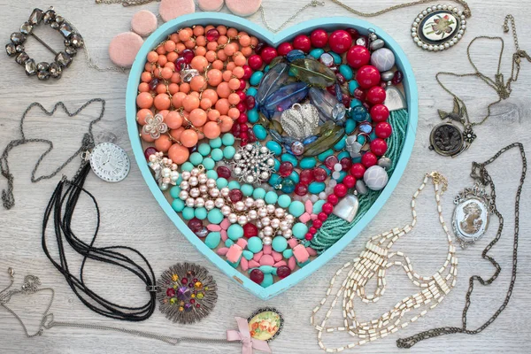 Un conjunto de joyas para las mujeres en una bandeja de madera en forma de corazón . —  Fotos de Stock