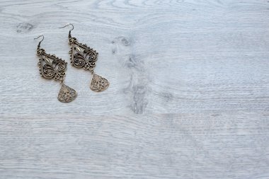 Vintage uzun küpe ahşap arka plan üzerinde metalden yapılmış.