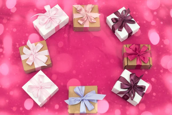 Подарочные коробки, связанные атласной цветной лентой на розовом фоне . — стоковое фото